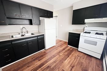 A kitchen with black cabinets and a white refrigerator.